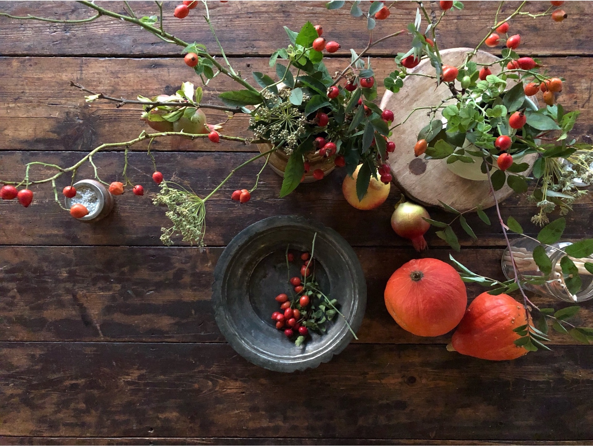 Autumn still life with berries, pumpkins and pomegranates on a weathered wooden table